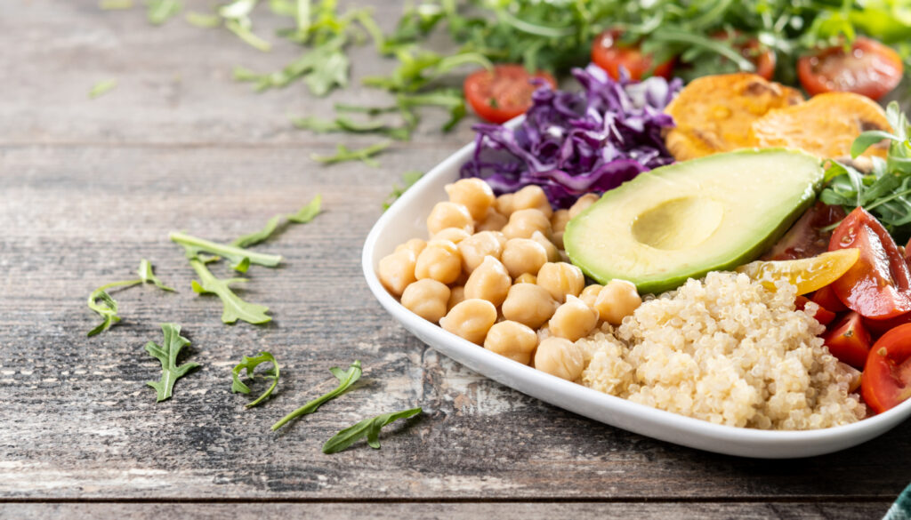 Salada saudável com abacate, tomate e grão-de-bico em uma mesa de madeira; dieta vegana